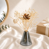 Ivory baby's breath with a wooden sola flower in a grey glass vase