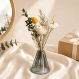 White daisy and yellow billy button with eucalyptus in a grey glass vase
