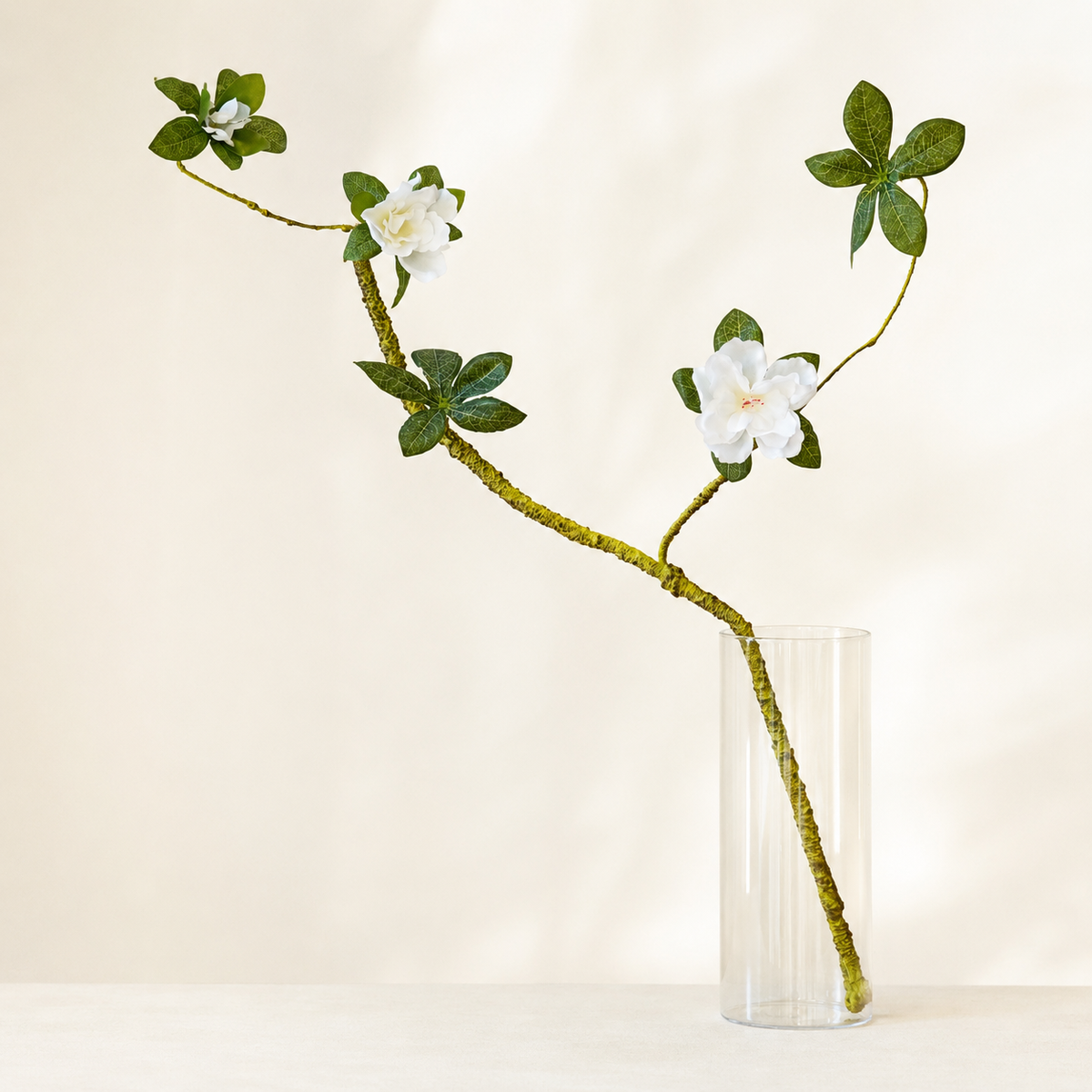 Minimalist faux gardenia branch with white blooms and dark green leaves
