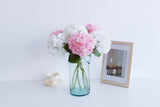 white and pink faux hydrangeas styled in a blue glass vase