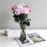 Pink and white faux roses in a grey glass vase on a magazine spread