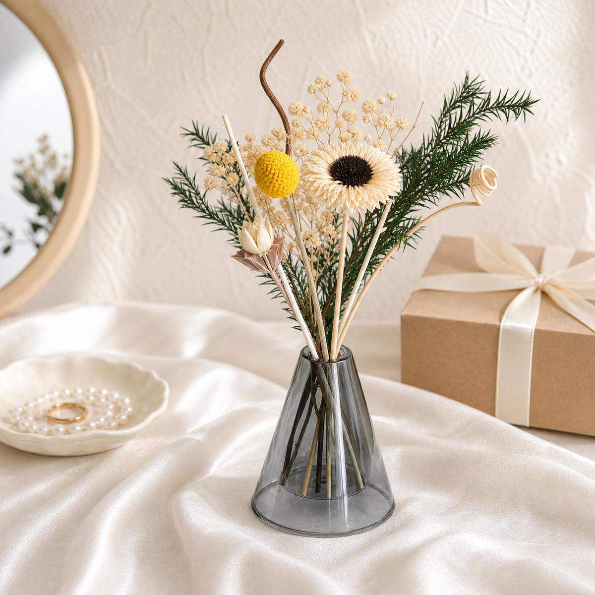 Cream sunflower with yellow craspedia and pine in a grey glass vase