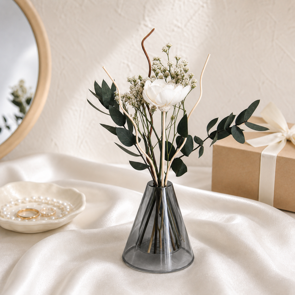 Small dried arrangement with a white bloom and eucalyptus in a grey glass vase