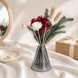 Red dried hydrangea with a white sola bloom, pine and bunny tails in a grey glass vase