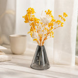 Yellow dried baby's breath with a white sola bloom in a grey glass vase