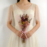 Blush and burgundy dried bouquet wrapped in pink tulle with a satin ribbon